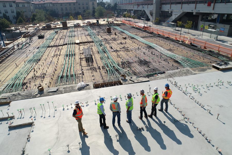 A line of workers in safety vests walking across a site